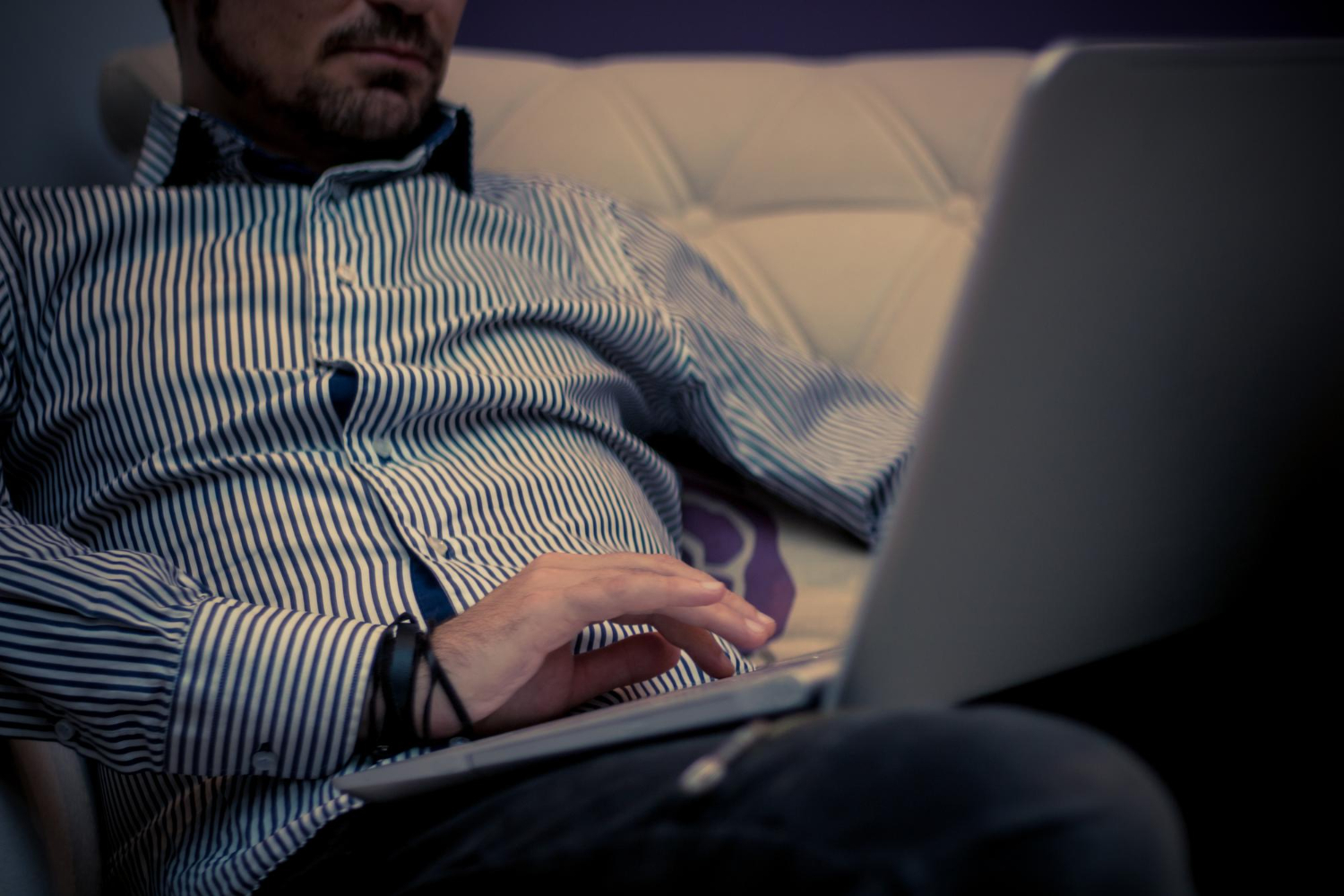 a man sitting on a sofa with a laptop on his lap